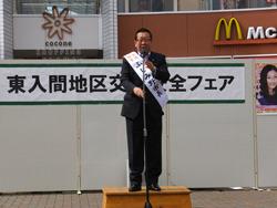 タスキをつけ、マイクの前で話す市長の写真