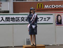 警察官の制服にタスキをつけ、マイクの前で話す、はいだ しょうこさんの写真