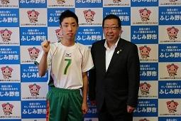 ユニフォームを着た嶋村 司さんが右手でガッツポースをして市長と一緒に写っている写真