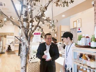 店の中の木の横で職員の人に話を聞いている市長の写真