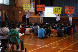 鶴ケ丘小学校の体育館で「認知症サポーター養成講座」を聞いている小学生や大人たちの写真