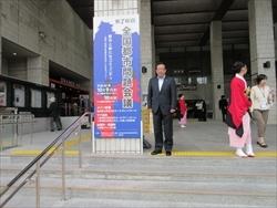 全国都市問題会議の看板の横で記念撮影している市長の写真