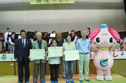 表彰を受けた方3名が賞状を持って、市長と関係者の男性とふじみんと一緒に舞台に立っている写真
