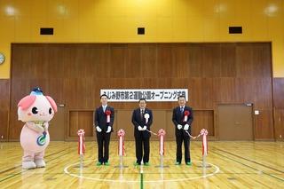 マスコットキャラクターの横でテープカットをしようとしている3人の人を写した写真