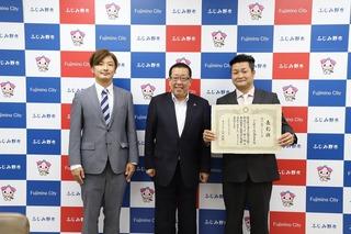 商工会青年部表敬訪問で右側の男性が賞状を持ち真ん中に市長、その隣にスーツ姿の男性と3人で並び写した写真