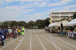 小学校のグラウンドの朝礼台で挨拶する市長の写真
