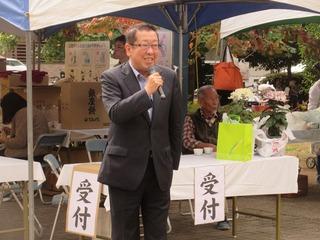 受付の前でマイクを片手に話をしている市長の写真