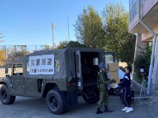 男子生徒が自衛隊車両に段ボールを運んでいるのを自衛官の男性が受け取っている写真