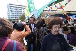 産業まつりの会場の模擬店には沢山のお客さんで賑わっており、模擬店の前を歩いている市長に市民の女性が話かけている写真