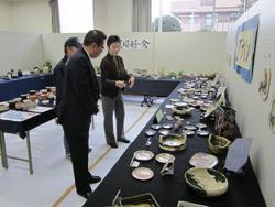 陶器の作品が並べてあり、その作品を見ながら話しをしている市長の写真