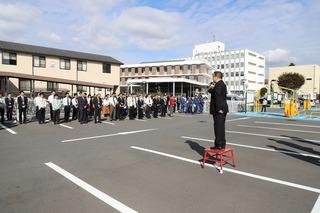 駐車場に職員の方々が集まっており、市長が台の上に立って話をしている写真