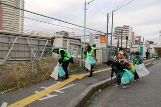 お揃いの緑の帽子を被りながら道路のごみを拾っている参加者達の写真