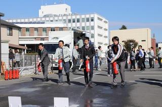 消火器を持ち消火活動の訓練をしている職員4人の写真