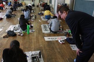床の上で書道をしている生徒達に話しかけている市長の写真