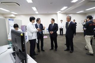 会場にテレビが設置されており、KDDI総合研究所の関係者の方が市長と関係者の方に話をしている写真