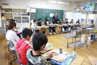 教室いっぱいに机を並べみんなで給食を食べている市長の写真