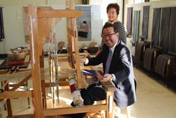 市長がはたおり機に座って笑顔で写っている写真