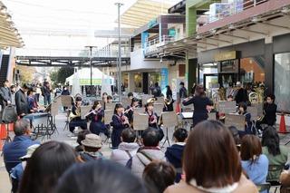 地元の中学校の吹奏楽の演奏が行われており、沢山のお客さんが演奏を聴いている写真