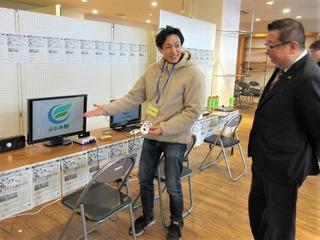 モニターを指す案内の人の説明を聞いている市長の写真
