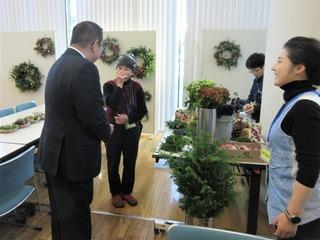 壁にリースが飾られた場所で女性と話をしている市長の後ろ姿の写真