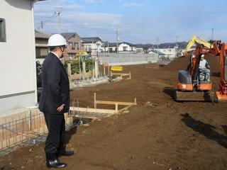 道路を整地している作業を見学しているヘルメット姿の市長の写真
