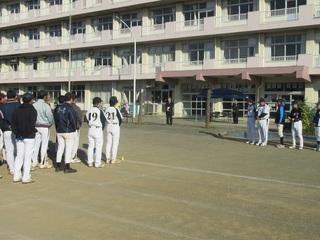 ソフトボール大会の参加者が、ユニフォームを着て整列をしている背後から、前方に市長が立っいる開会式の様子を写している写真