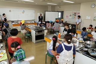 クッキング体験教室に多くの親子連れが参加し市長が挨拶をしている写真