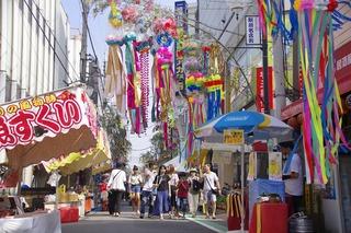 路上に屋台が並びたくさんの七夕飾りが飾られている写真
