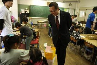 子ども達の机の周りを歩いて、子ども達の学習の様子を笑顔で見ている写真