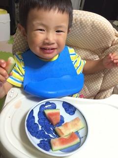 座っている男の子の赤ちゃんの前にお皿が置かれていて、お皿の上に食べ終わった後のスイカの皮が置かれている写真
