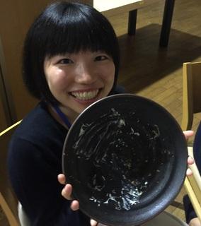 笑顔の女性が空になった大きなお皿を両手で持ち上げて見せている写真