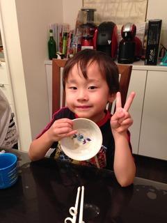 小さい男の子が右手には空になったお皿を見せていて、左手ではピースをしている写真