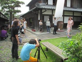 日本家屋の前の庭でピンク色の着物を着た女性の写真撮影をしている写真