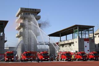 消防出初式にて消防訓練場の建物に向かって放水演習が行われている写真