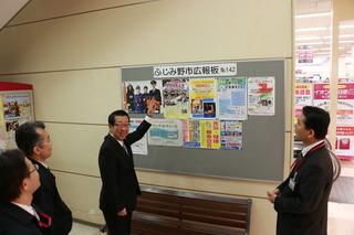 イオン大井店に設置されている広報版を指さす市長の写真