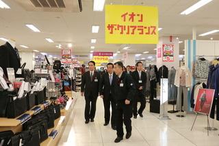 イオン大井店にて男性スタッフより衣料品コーナーを案内される市長の写真