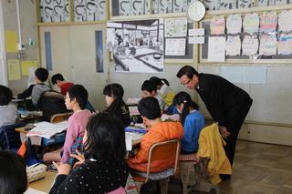 福岡小学校にて後ろの席で授業を受けている生徒を見学している市長の写真