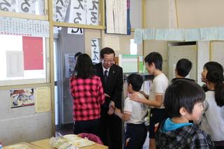 福岡小学校にて教室の出入口で生徒と握手をしている市長の写真
