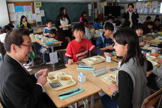 駒西小学校にて給食の時間に隣の席の女子生徒と話をしている市長の写真