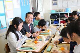 東原小学校の生徒と一緒に給食を笑顔で食べる市長の写真