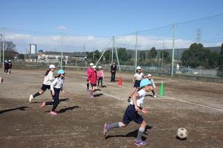 西原小学校のグラウンドにて生徒たちがサッカーをしている写真