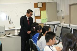 鶴ケ丘小学校にて授業でコンピュータの操作をしている生徒を見学する市長の写真