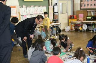 鶴ケ丘小学校にて教室の床で作業している生徒を見学する市長の写真