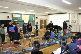 鶴ケ丘小学校にて音楽室で歌の練習をする生徒を見学している市長の写真