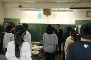 鶴ケ丘小学校にて教壇での市長の話を立って聞いている生徒たちの写真