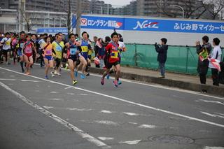 駅伝競走大会にてゼッケンをつけた選手を沿道の人たちが応援している写真