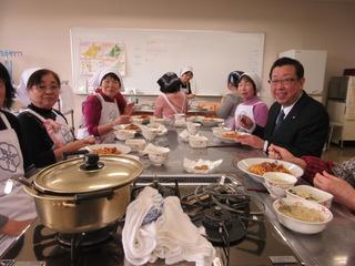 出来上がった料理を参加者の女性の皆さんと一緒に食べている市長の写真