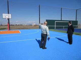 青いフィールドのバスケットコートを見学している市長の写真