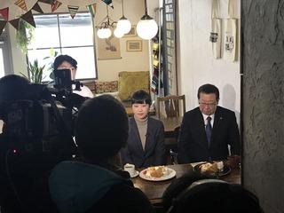 テーブルに料理が置かれ客席に座り撮影をされている市長の写真