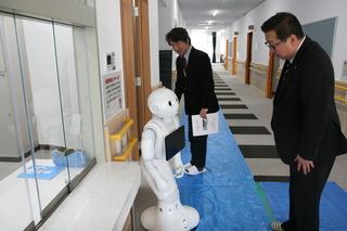 廊下に置いてあるロボットのペッパー君を見ている市長の写真